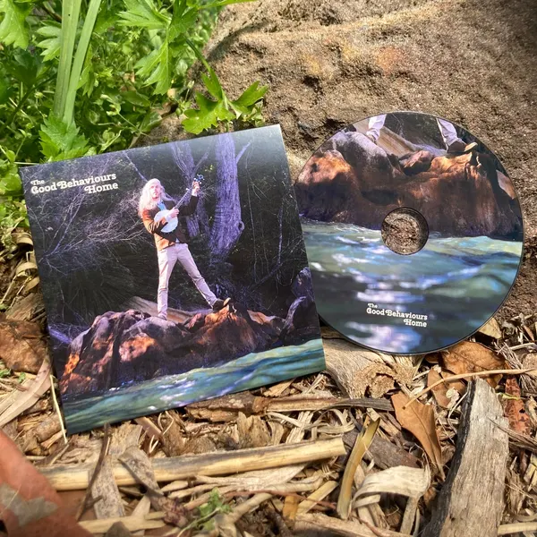 The Home CD in its cardboard sleeve, lying on bark and leaves