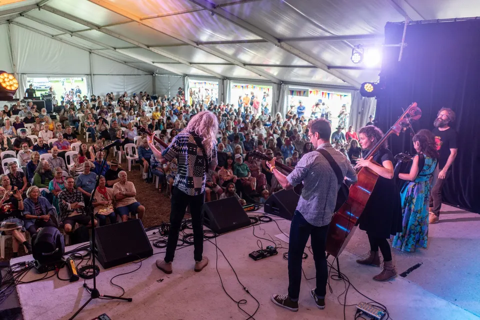 The band playing to a packed festival marquee, seen from behind the stage
